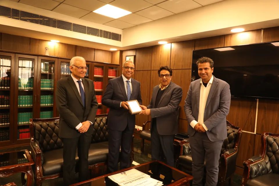 Guests of the Centre presenting a memento in a wood-panelled office.